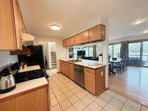 A modern kitchen with wooden cabinets, a stainless steel stove, and a dishwasher.