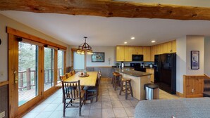 A modern kitchen with wooden cabinets, a central island, and a dining area with rustic chairs. - Hibernation House at Lutsen, Hibernation House at Lutsen (Lutsen)
