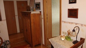 Een kamer met houten deuren, een tafeltje met een lamp en een muur met ingelijste foto's.