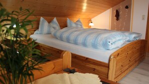 Een houten bed met hoofdeinde, een bedlampje en een decoratie aan de muur.