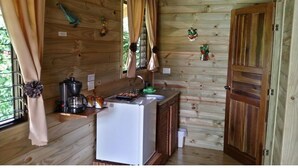 Uma cabana de madeira compacta com cozinha compacta, incluindo geladeira, cafeteira e pia.