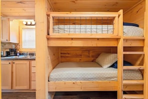 A bunk bed with a kitchen area visible in the background. - Lena Cabin in Chattanooga' Premier Rustic Resort (Chattanooga)