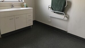 A bathroom with a white sink, a green towel, and a grab bar. - Irishman Drive Retreat, free wifi. (Twizel)