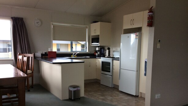 A compact kitchen with a dining area, a sink, a stove, and a refrigerator. - Irishman Drive Retreat, free wifi. (Twizel)
