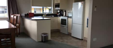 Une cuisine compacte comprenant un coin repas, un évier, une cuisinière et un réfrigérateur.