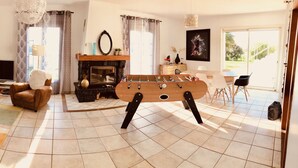 Ein Wohnzimmer mit einer Couch, Fernseher, Kamin und einem Kicker.