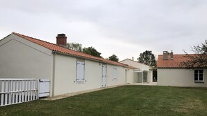 Eine Reihle weißer Gebäude mit roten Ziegel-Dächern, einem grünen Rasen und einem weißen Zaun.