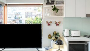Eine moderne Küche mit Flachbildfernseher, weißen Schränken, einer Mikrowelle und Blick auf die Stadt.