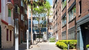 Kapea kaupunkikatu, jonka varrella on useita kerroksia sisältäviä rakennuksia, keskeinen portaikko ja pieni aukiotorialue.