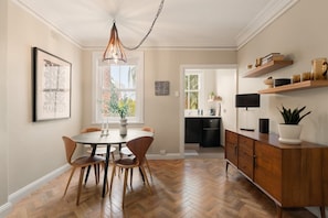A dining area with a herringbone floor, a round table, and wooden chairs.