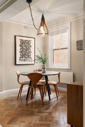 A dining area with a round table, chairs, and a hanging light fixture.