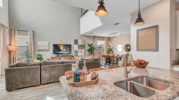 A modern kitchen with granite countertops, a stainless steel sink, and pendant lighting.