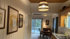 Un interior de madera con comedor, una cocina con fregadero y cuadros en la pared.