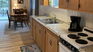 Una cocina con armarios de madera, encimera de granito, estufa y comedor con mesa y sillas.