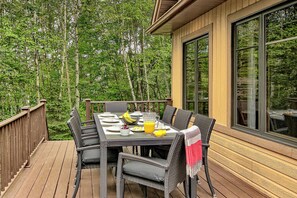 Eine Terrasse mit Esstisch und Stühlen, mit Blick auf ein bewaldetes Gebiet.
