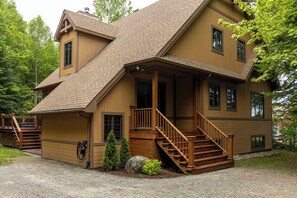 Eine zweistöckige Blockhütte mit Veranda, Treppe und überdachter Terrasse.