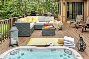 Una terraza con jacuzzi, mobiliario exterior y vistas a los árboles circundantes.