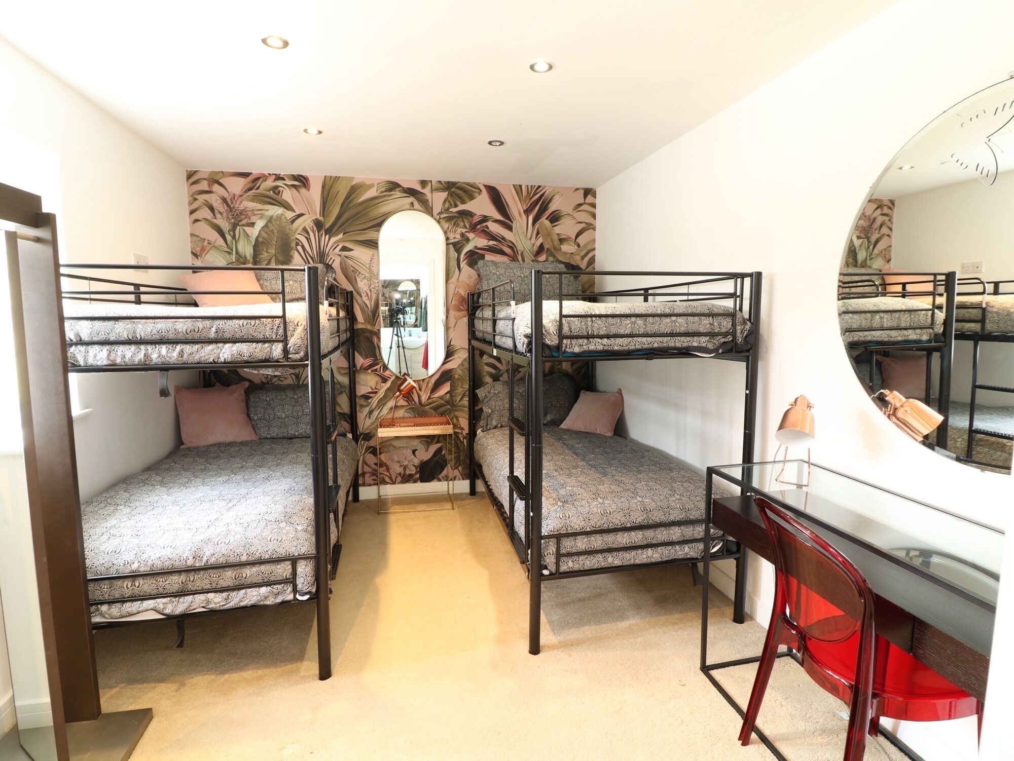 Une chambre de dortoir avec des lits superposés, un bureau et un miroir.