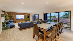 A spacious living area with a large TV, comfortable seating, and a dining table. - Lincoln 4-beds, Sleeps 13, Hot Tub & Pet Friendly (Lincoln)