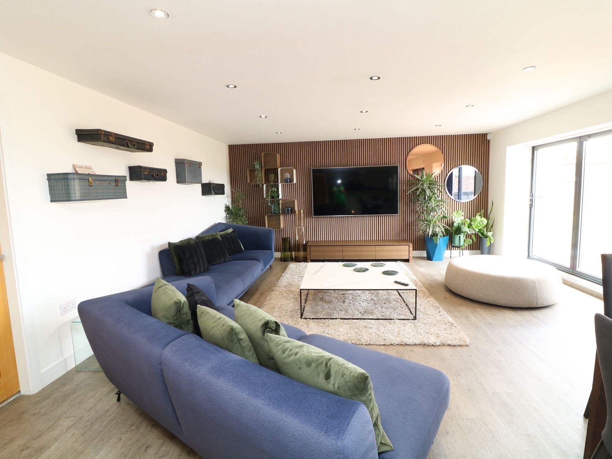 Ein modernes Wohnzimmer mit einem blauen Sofa, einem Couchtisch und einem an der Wand montierten Flachbildfernseher.