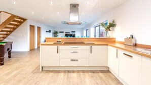A modern kitchen with a wooden island, built-in appliances, and a staircase leading to another level. - Lincoln 4-beds, Sleeps 13, Hot Tub & Pet Friendly (Lincoln)