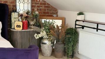 Une pièce chaleureuse avec un mur en briques, un grand miroir et une variété de plantes en pot.