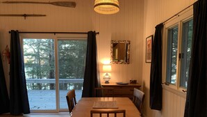 Een houten eettafel met stoelen, een lamp en een raam met gordijnen.