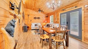A wooden interior with a dining table, chairs, a chandelier, a ceiling fan, and a sign reading 'MOONSHINE.' - Holy Smokes - 2 bdrms/2 bath, fire pit, pet friendly with yard (Townsend)