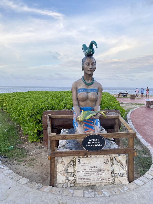A statue of a woman holding a fish, with a plaque in front of it.