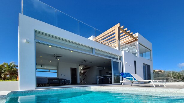 A modern two-story house with a glass facade, a swimming pool, and a wooden pergola. - VILLA CASCADA- Lux private gated villa with elevator, Private Gated Luxury Oceanview Villa with Elev (Isla Mujeres)