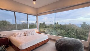 A modern bedroom with a large bed, a round bean bag, and a view of the outdoors through large windows. - VILLA CASCADA- Lux private gated villa with elevator, Private Gated Luxury Oceanview Villa with Elev (Isla Mujeres)