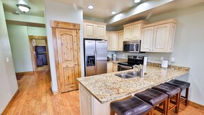 Una cucina moderna con mobili in legno, un frigorifero in acciaio inossidabile, un forno a microonde e un piano di lavoro in granito.