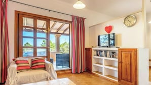 Una habitación acogedora con una cama, una mesa de madera, un televisor y una estantería.