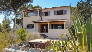 Una casa de dos pisos con un patio, rodeada de rocas y cactus.