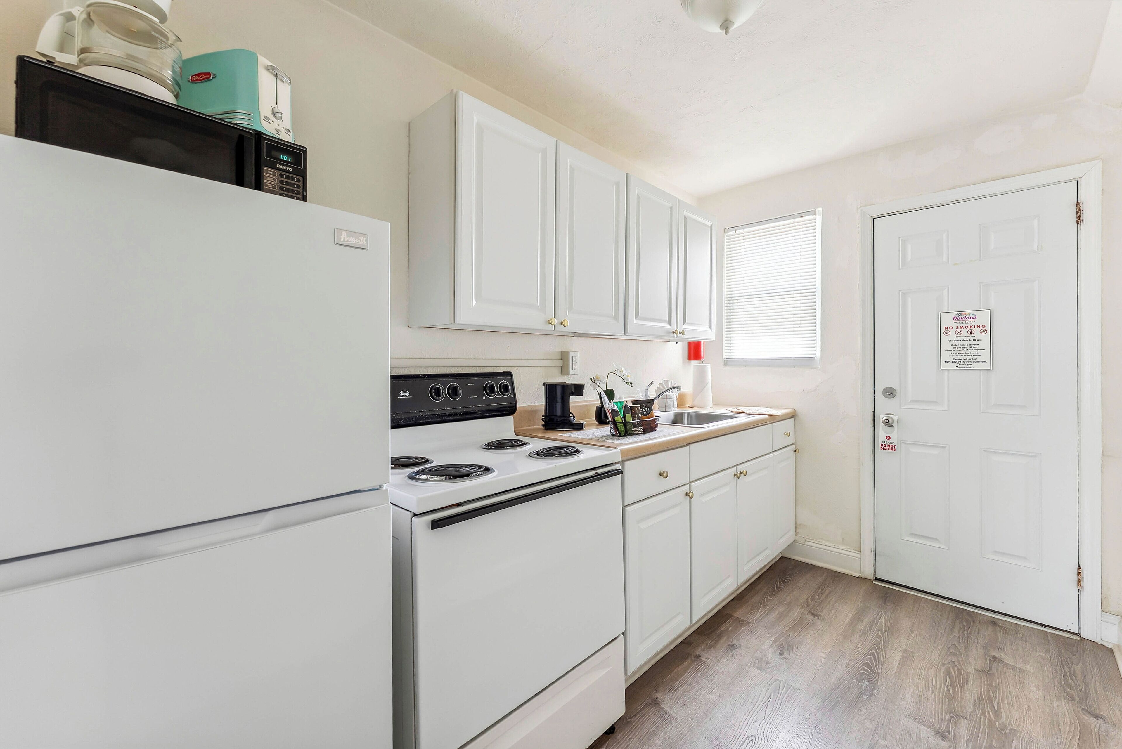 A kitchen with white cabinets, a stove, a microwave, and a sink.