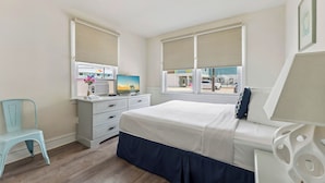 A bedroom with a bed, a dresser, a chair, and a window with blinds.
