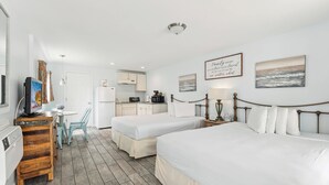 A hotel room with two beds, a kitchenette, a dining area, and artwork on the walls. - Daytona Inn and Suites - Efficiency Queen (Wildwood)