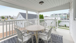 A covered balcony with a white railing, a round table, and four white chairs. - Daytona Inn and Suites - Three Bedroom Apartment (Wildwood)