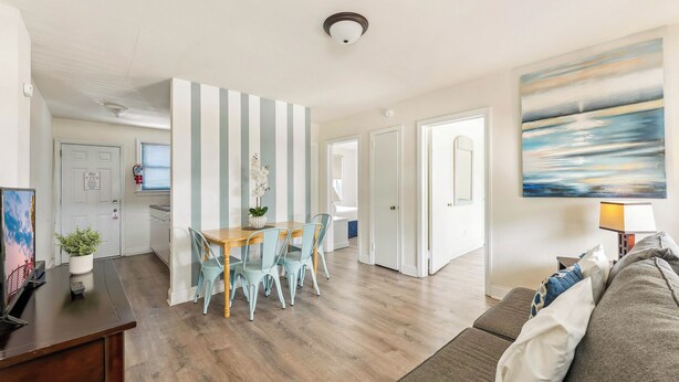 Een moderne woonkamer met een houten vloer, een eethoek met gestreepte wanden en een schilderij aan de muur.