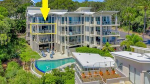 A multi-story hotel with a pool, outdoor seating, and lush greenery.