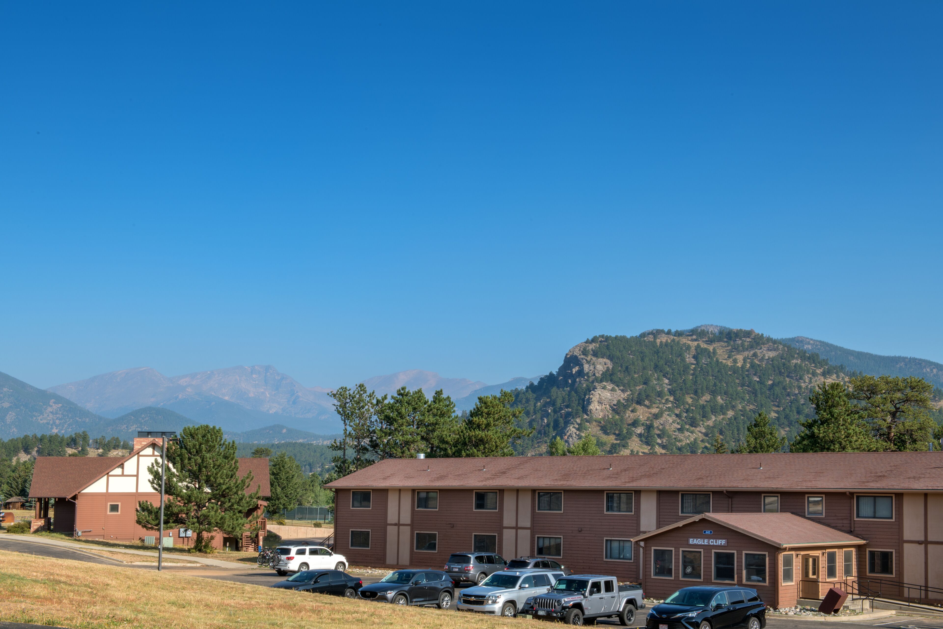 A motel with a parking lot, a mountain backdrop, and a sign reading "Eagle Cliff".