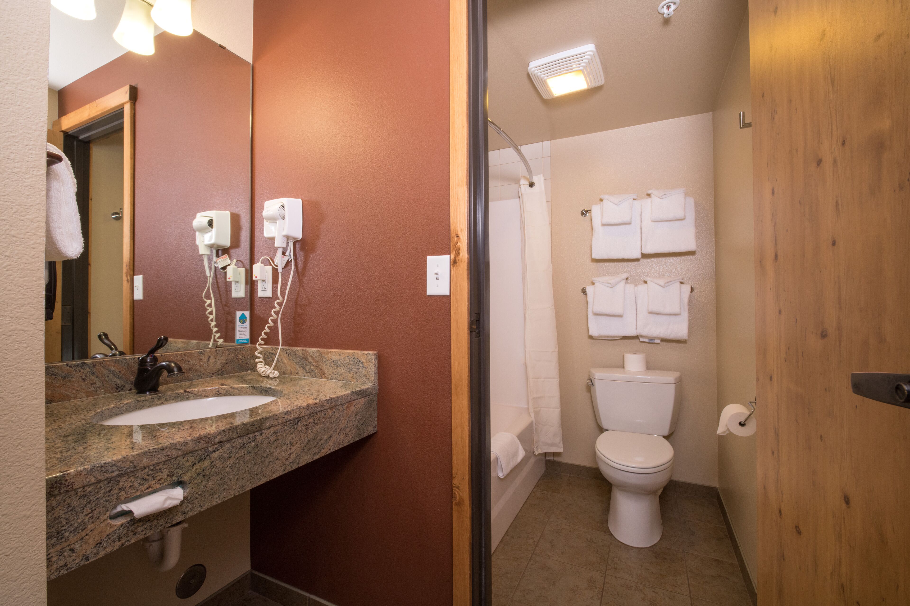 Une salle de bain équipée d’un lavabo en granit, d’un miroir, d’un sèche-cheveux et d’une douche.