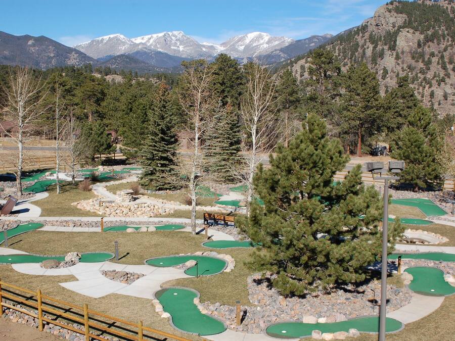 A golf course with multiple green areas and a wooden fence.