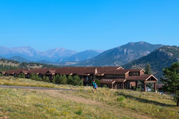 Un albergue con varias construcciones, cielo despejado y montañas al fondo.