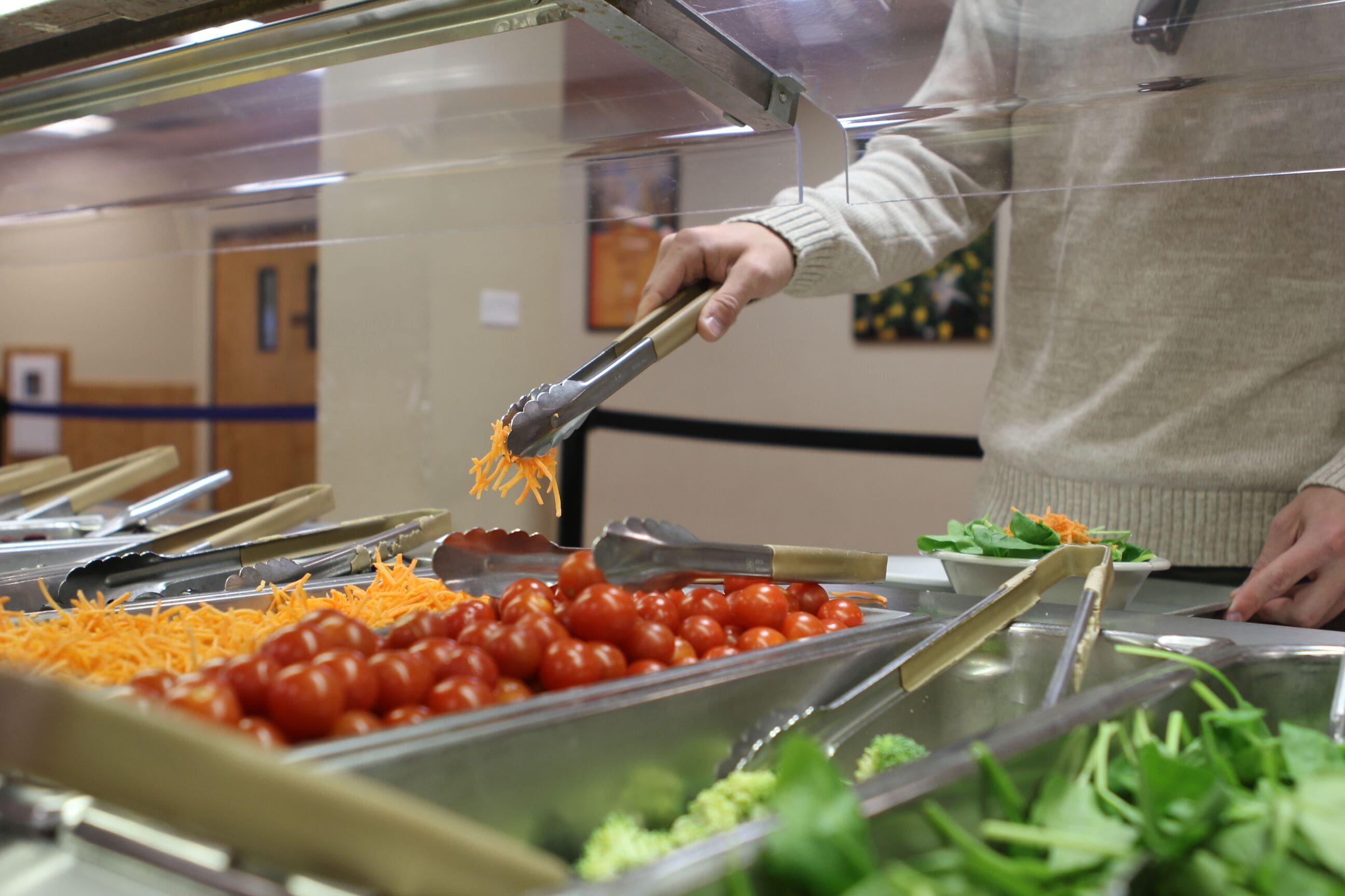 Un buffet proposant une variété d’aliments, notamment du fromage râpé, des tomates cerises et des légumes verts.