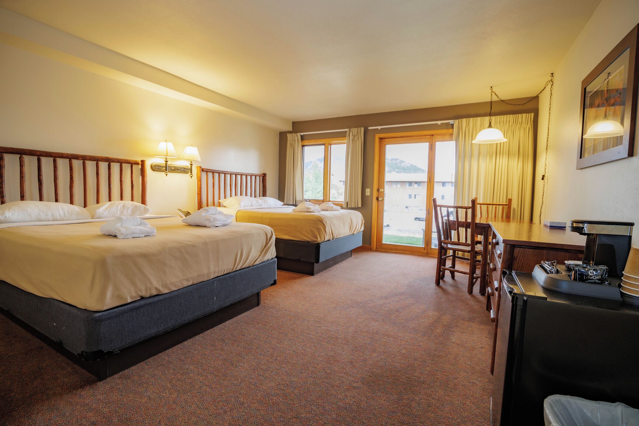 Een hotelkamer met twee bedden, een bureau en een stoel.