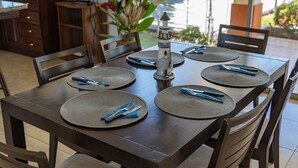 Mesa posta com jogos americanos, talheres e um centro de mesa decorativo com um farol.