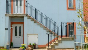 A two-story house with a front entrance, a staircase, and a small balcony. - Little Acorn - 2-bed Anstruther Apartment (Anstruther)