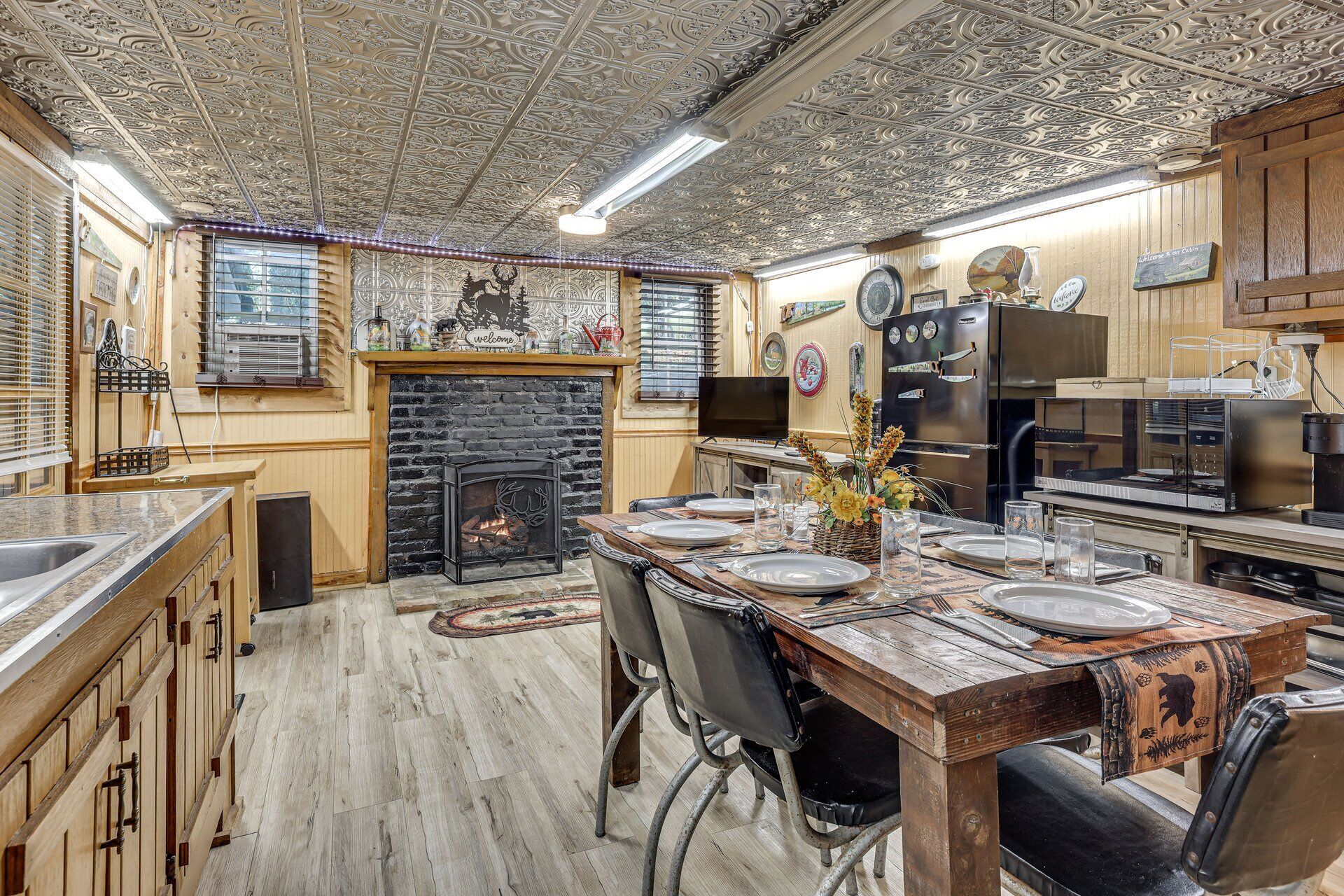 A rustic kitchen with a fireplace, wooden cabinets, and a dining table set for four.