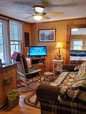 Relax in this inviting room with a sofa, TV, and ceiling fan.